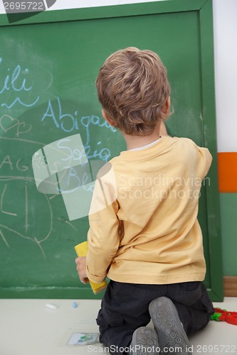 Image of Boy Writing On Chalkboard At Kindergarten