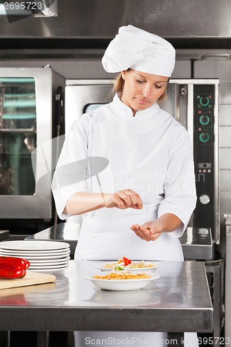 Image of Female Chef Garnishing Dish At Counter