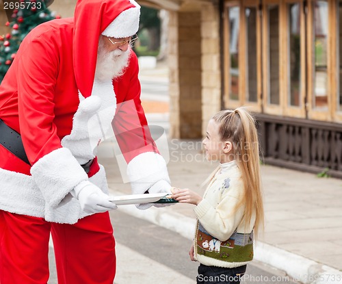 Image of Santa Claus Offering Cookies To Girl