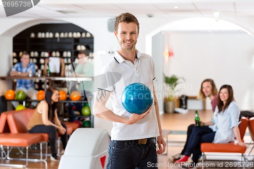 Image of Young Man Holding Blue Bowling Ball in Club