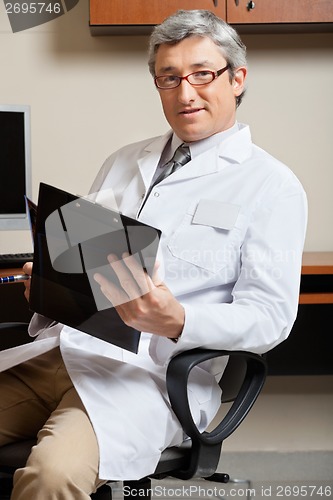 Image of Mature Doctor Holding Clipboard