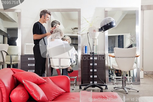 Image of Hairstylist Straightening Client's Hair At Salon