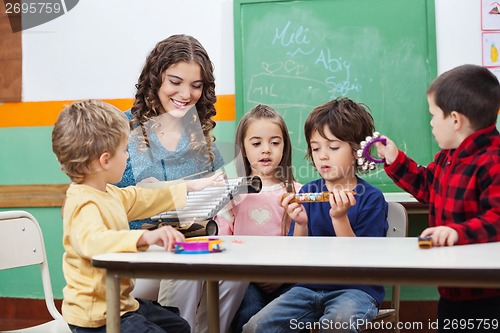 Image of Children And Teacher Playing With Musical Instruments