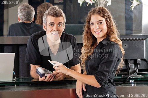 Image of Hairdresser With Woman Paying Through Cellphone At Counter