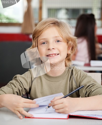 Image of Portrait Of Schoolboy Writing In Book At Desk