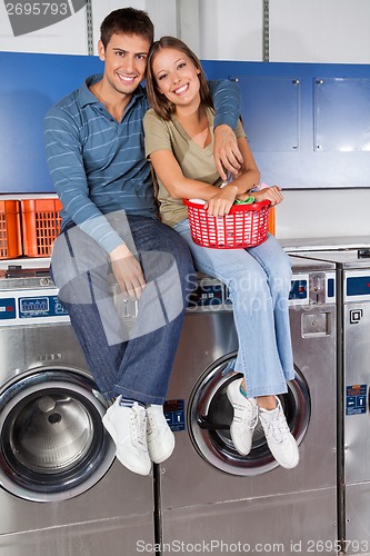 Image of Happy Young Couple Sitting On Washing Machines