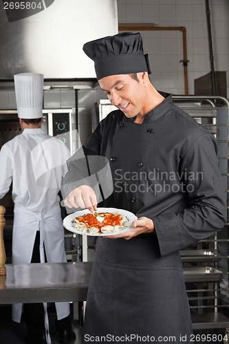 Image of Chef Garnishing Dish In Kitchen