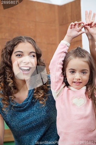 Image of Teacher And Little Girl With Hands Raised