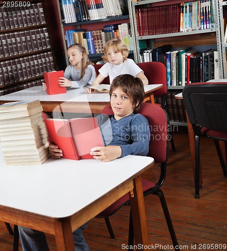 Image of Schoolboy With Books Sitting At Library