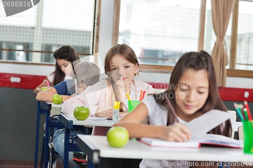 Image of Schoolgirl Sitting At Desk With Classmates In A Row