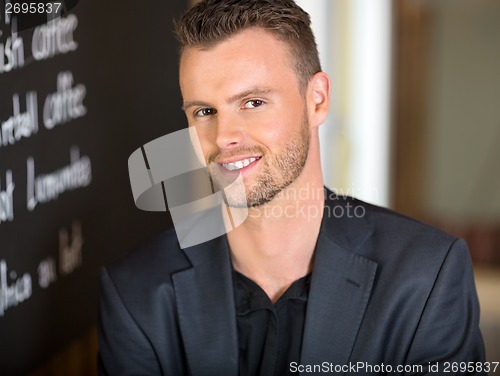 Image of Businessman Next To Menu Board In Coffeeshop