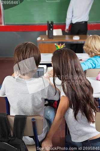 Image of Schoolchildren Using Digital Tablet In Classroom