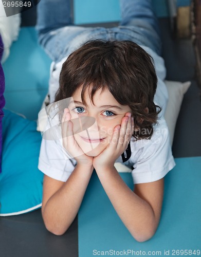 Image of Boy With Head In Hands Lying On Floor In Preschool