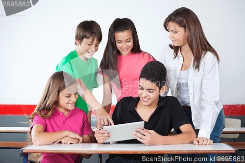 Image of Schoolboy Pointing At Tablet With Classmates In Classroom