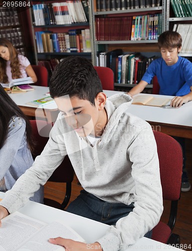 Image of Male Student Reading Book In Library