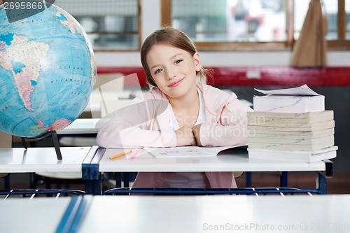 Image of Cute Schoolgirl Sitting With Globe And Stacked Books