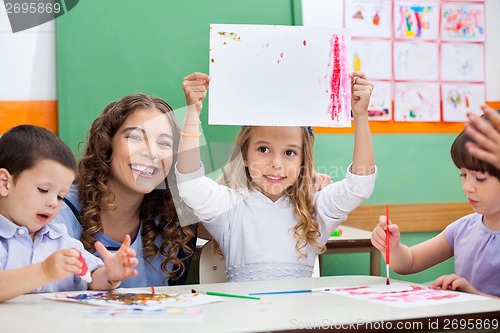 Image of Teacher With Girl Showing Drawing At Desk