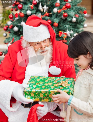 Image of Santa Claus Giving Gift To Girl