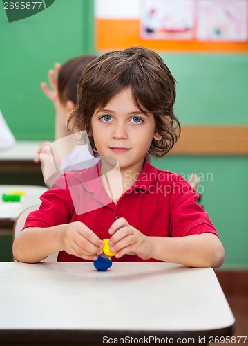 Image of Boy Holding Clay Model At Desk