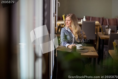 Image of Woman With Coffee Cup Sitting At Table At Cafe