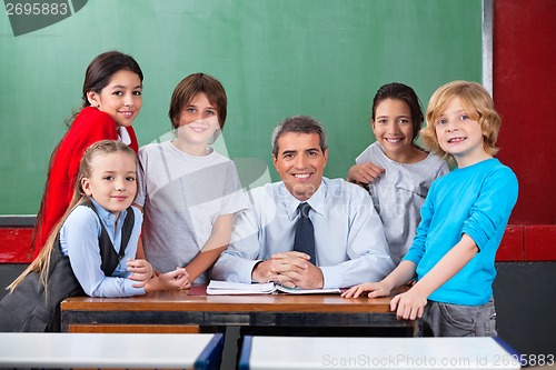 Image of Confident Male Teacher With Schoolchildren  At Desk