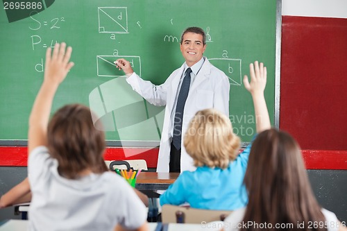 Image of Teacher Teaching While Students Raising Hands