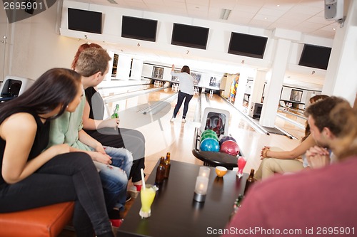 Image of Friends Watching Woman Bowling in Alley