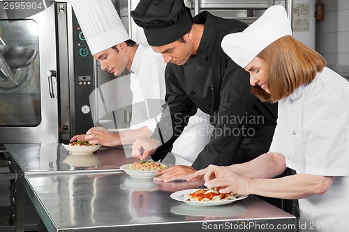 Image of Chefs Garnishing Dishes On Counter