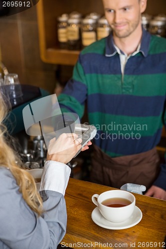 Image of Woman Making Payment Through Mobilephone