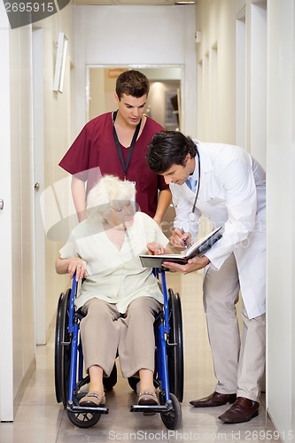 Image of Medical Professionals With Patient In Corridor