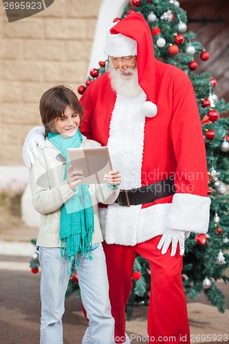 Image of Boy Showing Digital Tablet To Santa Claus