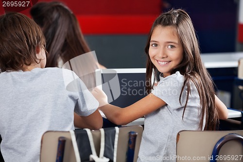 Image of Schoolgirl Holding Digital Tablet At Desk In Classroom