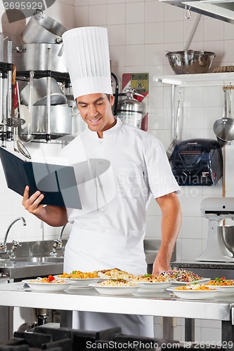 Image of Chef With Checklist And Pasta Dishes At Counter