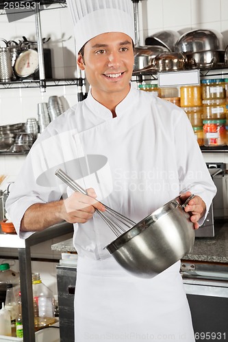Image of Male Chef Whisking Egg In Kitchen