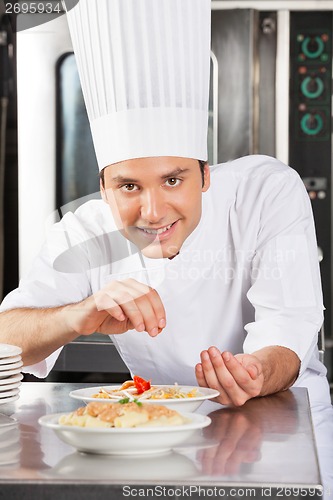 Image of Happy Male Chef Sprinkling Spices On Dish