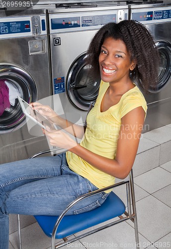 Image of Young Woman With Digital Tablet In Laundry