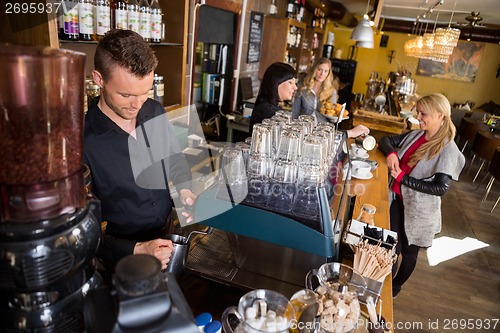Image of Bartender Working At Counter While Female Colleague Serving Coff