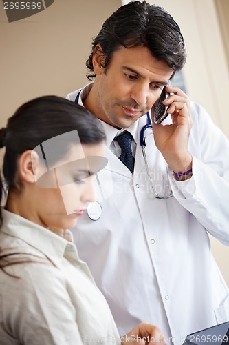 Image of Doctor Attending Call While Standing With Colleague