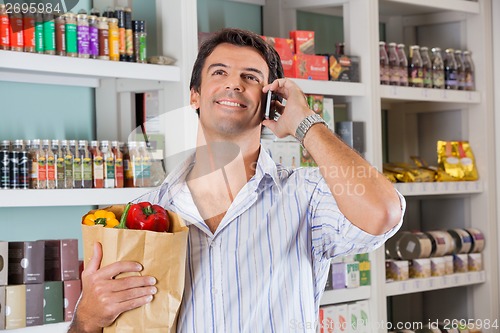 Image of Man With Paper Bag Using Cellphone In Market