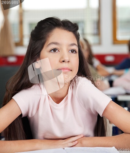 Image of Thoughtful Schoolgirl Looking Away While Sitting At Desk