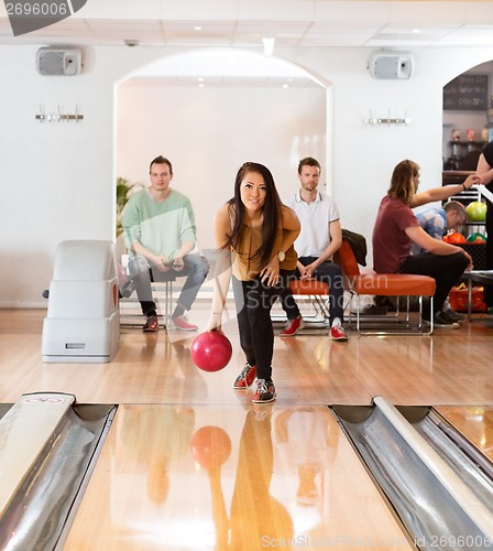 Image of Woman Throwing Bowling Ball in Club