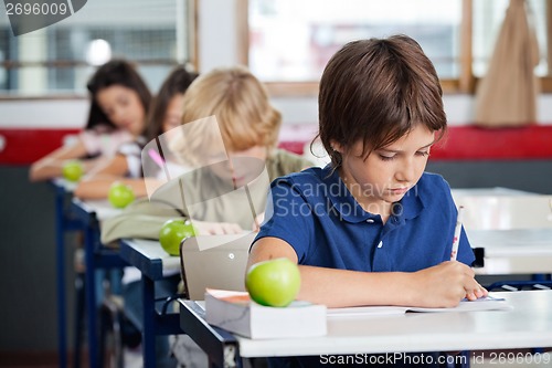 Image of Boy Studying At Desk In Classroom