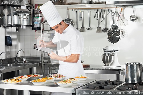 Image of Chef With Clipboard Going Through Cooking Checklist