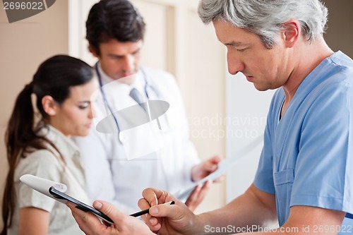 Image of Doctor Writing On Clipboard