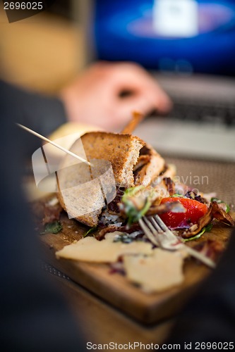 Image of Half Eaten Sandwich On Wooden Plate