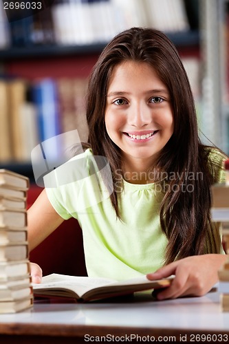 Image of Happy Schoolgirl Sitting At Table In Library
