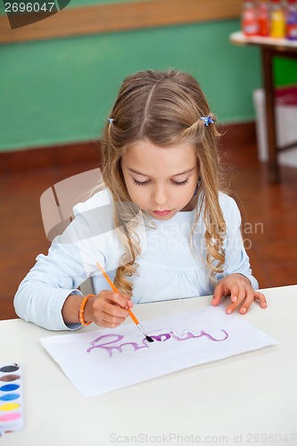 Image of Girl Painting Name On Paper At Desk