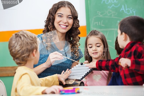 Image of Teacher And Children Playing With Xylophone In Classroom