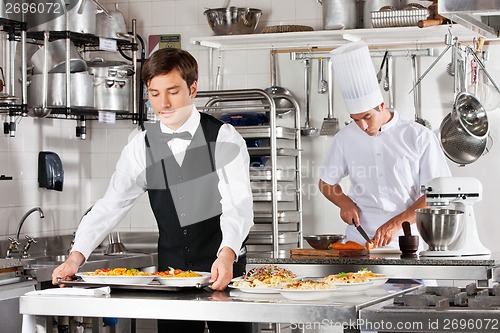 Image of Waiter And Chef Working In Kitchen