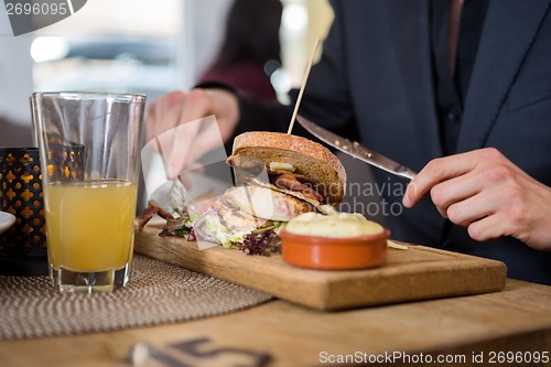 Image of Young Businessman Having Sandwich In Cafe